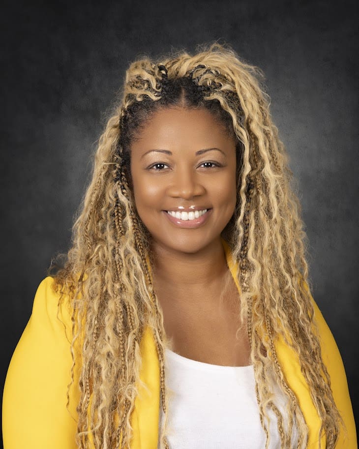 Smiling woman with blonde dreadlocks, yellow blazer