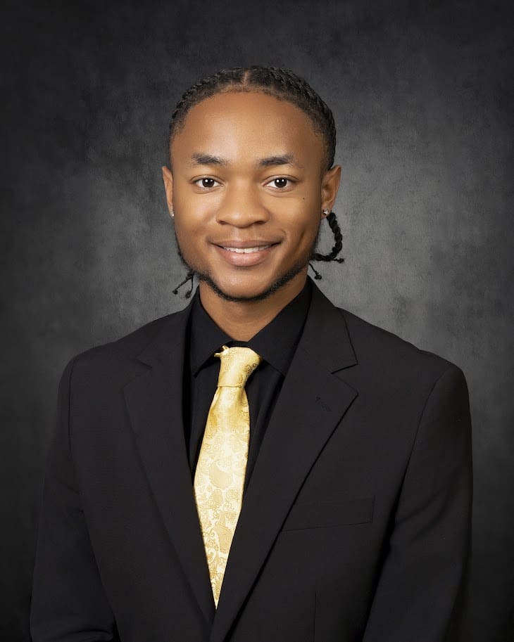 Smiling man in black suit with gold tie
